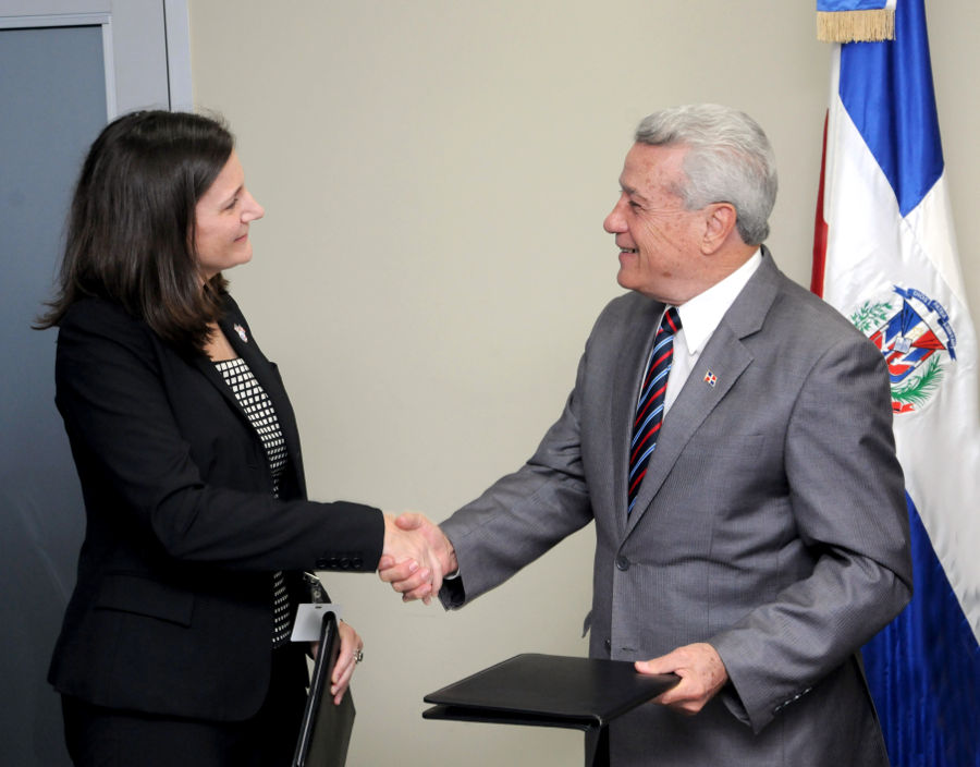 Kristin Kaper, directora del Cuerpo de Paz y Nelson Toca Simó, titular del MICM, se estrechan las manos al momento de firmar el acuerdo.