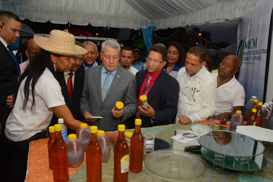 El ministro Nelson Toca Simó en el stand del MICM mientras recibe información de productos emblemáticos de la ciudad junto al director provincial, Rafael Lockhart.